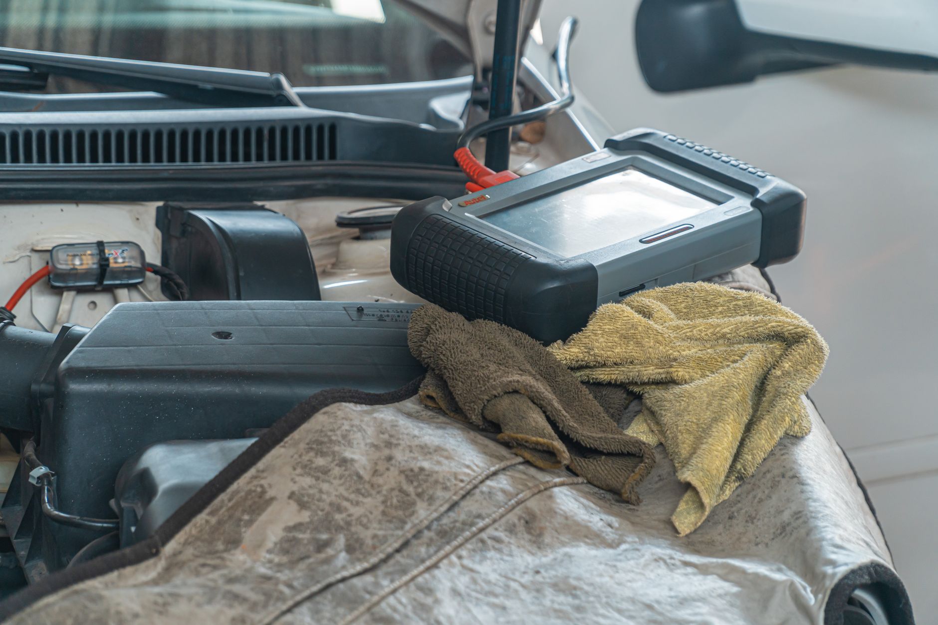 Representative close-up of a diagnostic scanner resting beside an open engine compartment.